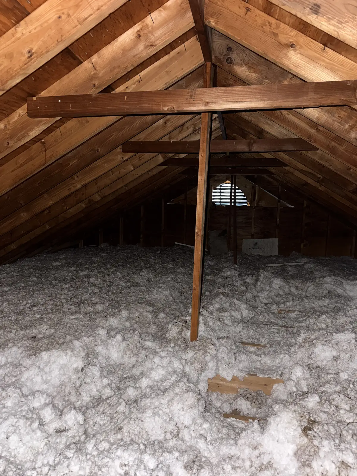 An attic floor covered in old, matted gray insulation